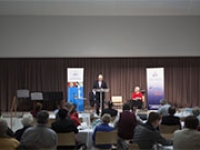 Rows of people in an audience listening to a speaker